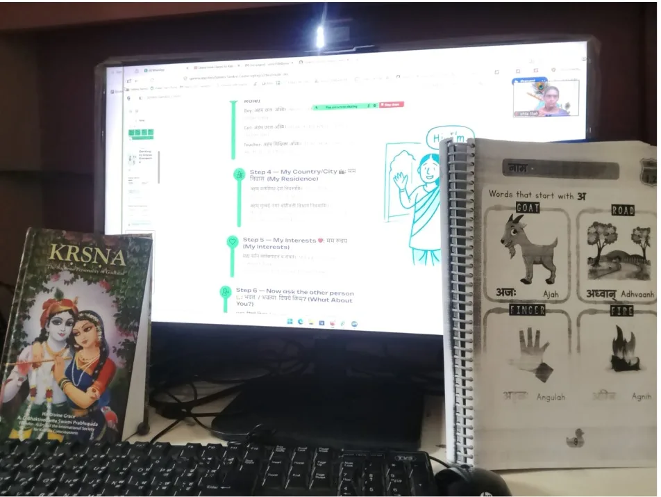 A lesson on screen beside the printed student workbook